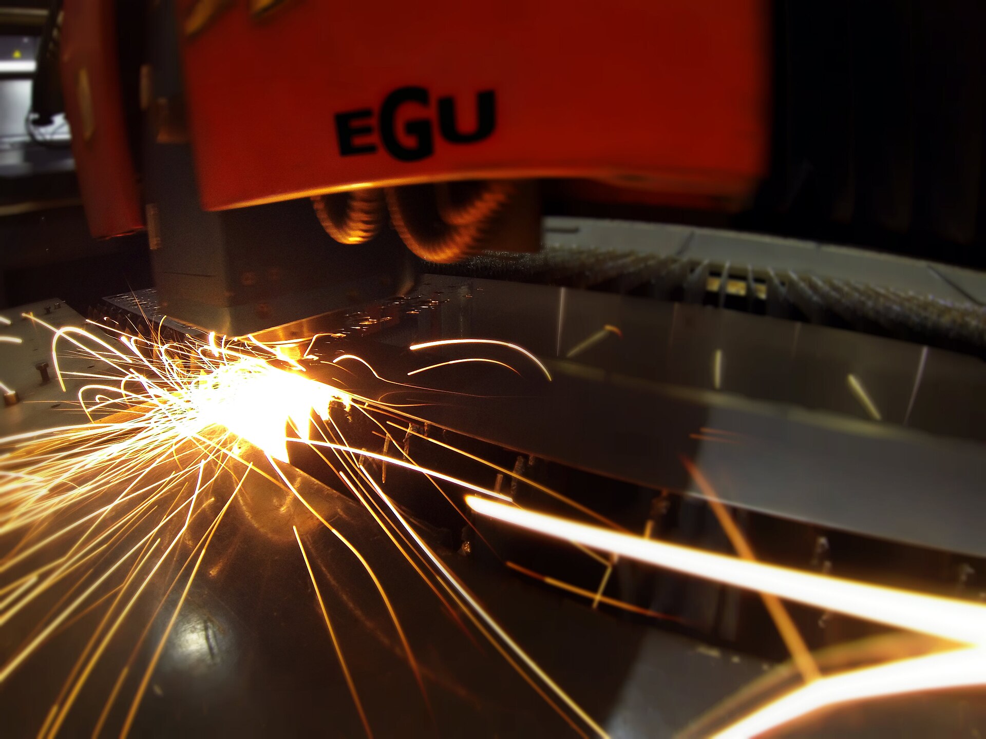 Découpe laser d’une tôle en acier avec projection d’étincelles